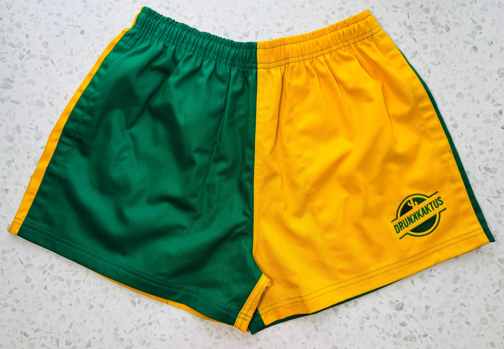 Green gold cotton shorts laid flat showing elastic waistband and drawstring