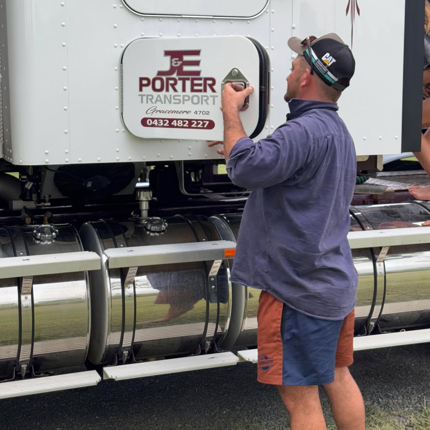 Model wearing navy and chocolate cotton drill shorts in a casual outdoor setting