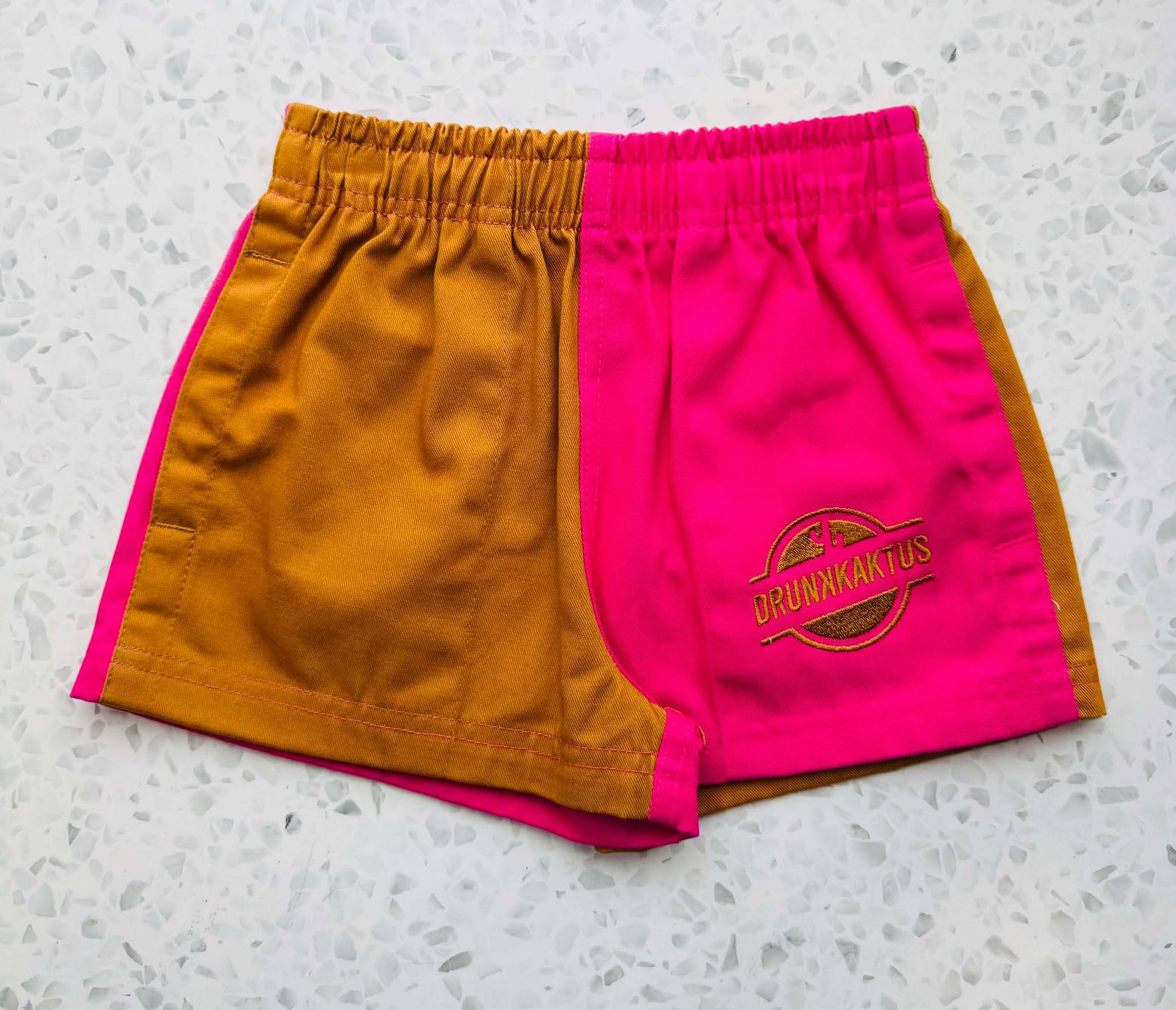 Front view of kids mustard pink ruggers cotton drill shorts with elastic waistband and drawstring.