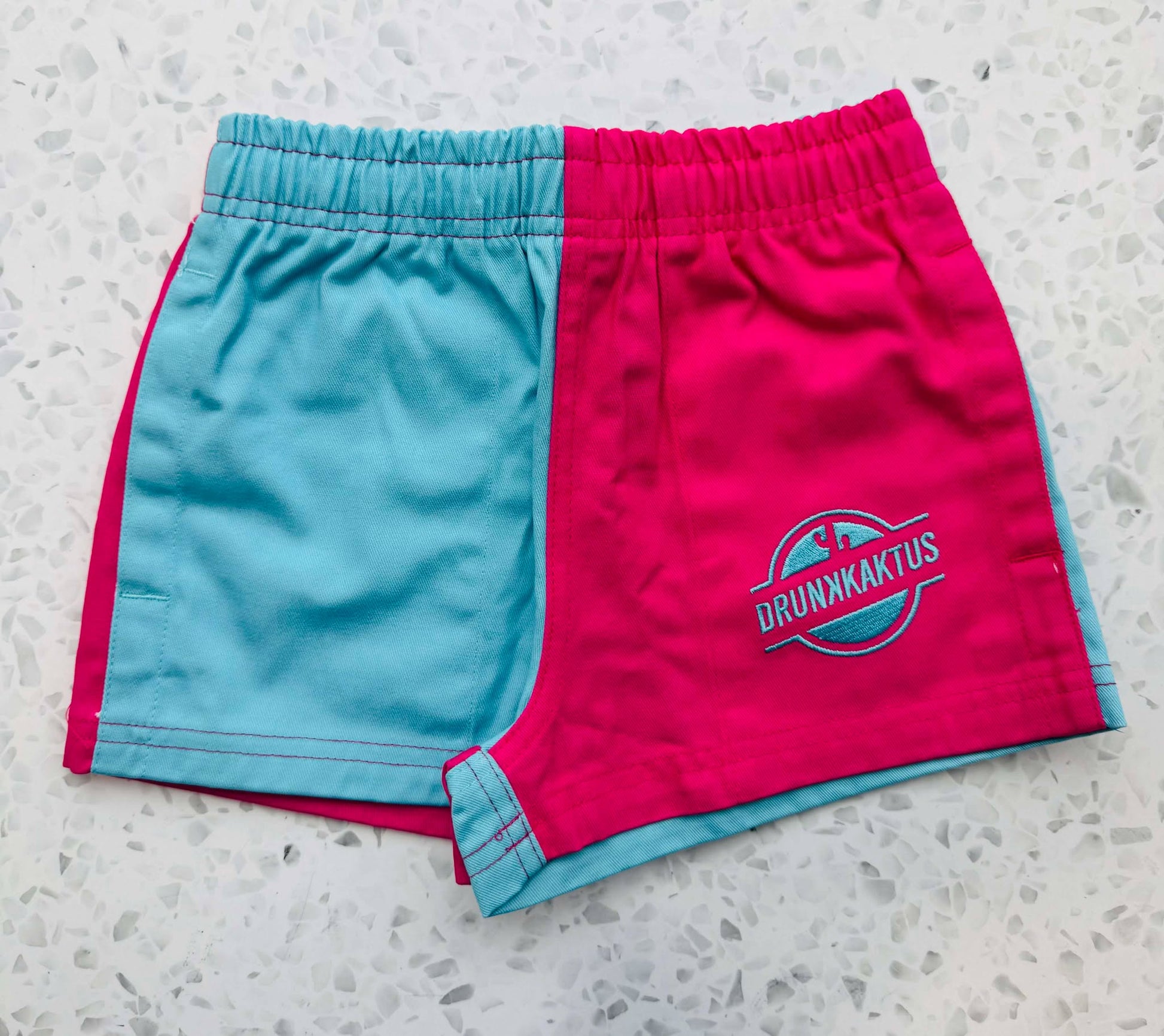 Front view of kids ruggers blue pink cotton drill shorts showing elastic waistband and drawstring.