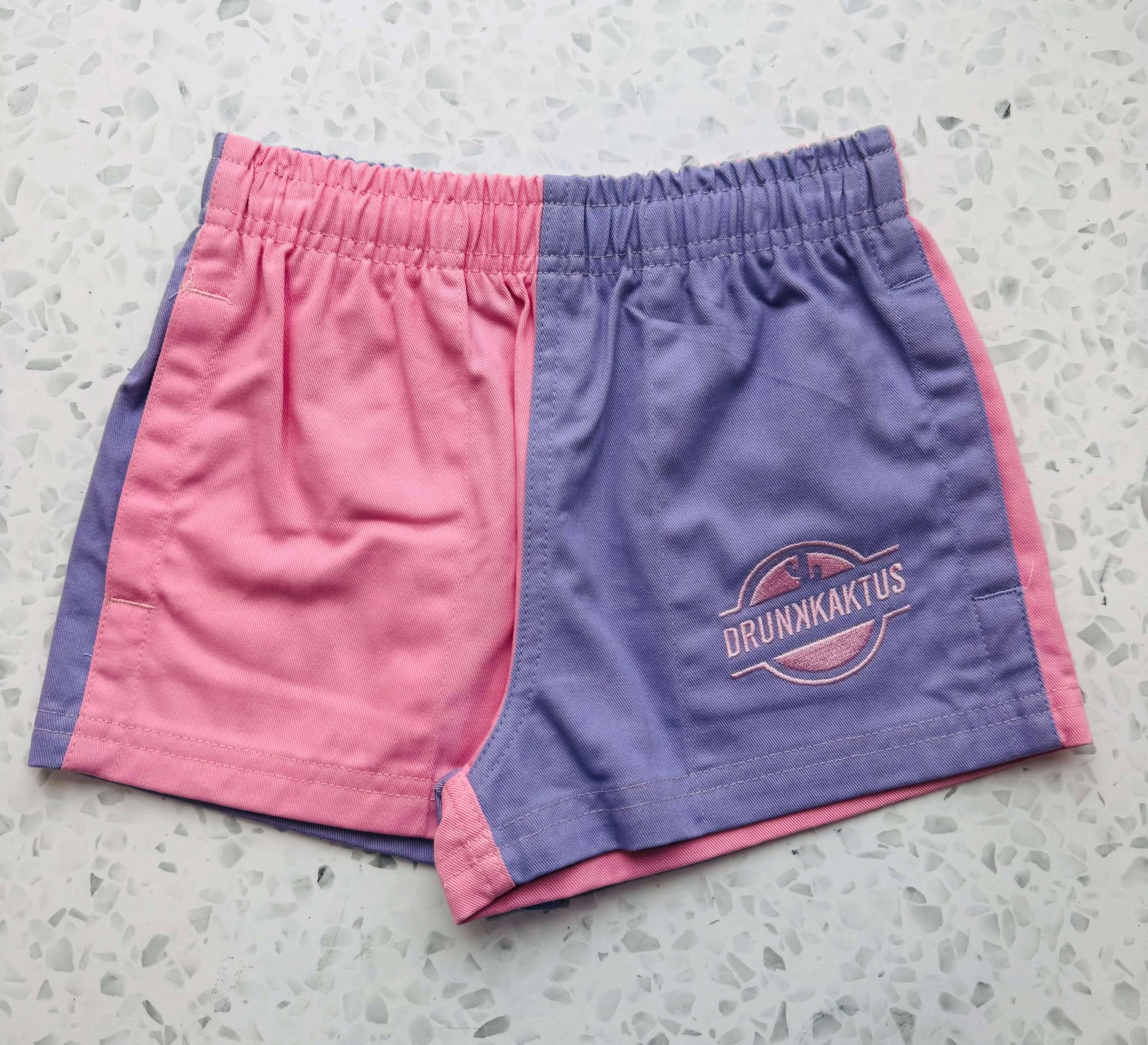 Front view of kids pink purple shorts made from cotton drill fabric, showing elastic waistband and drawstring for a comfortable fit.