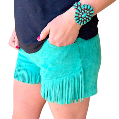 Turquoise suede shorts with fringe and a person wearing them on a white background